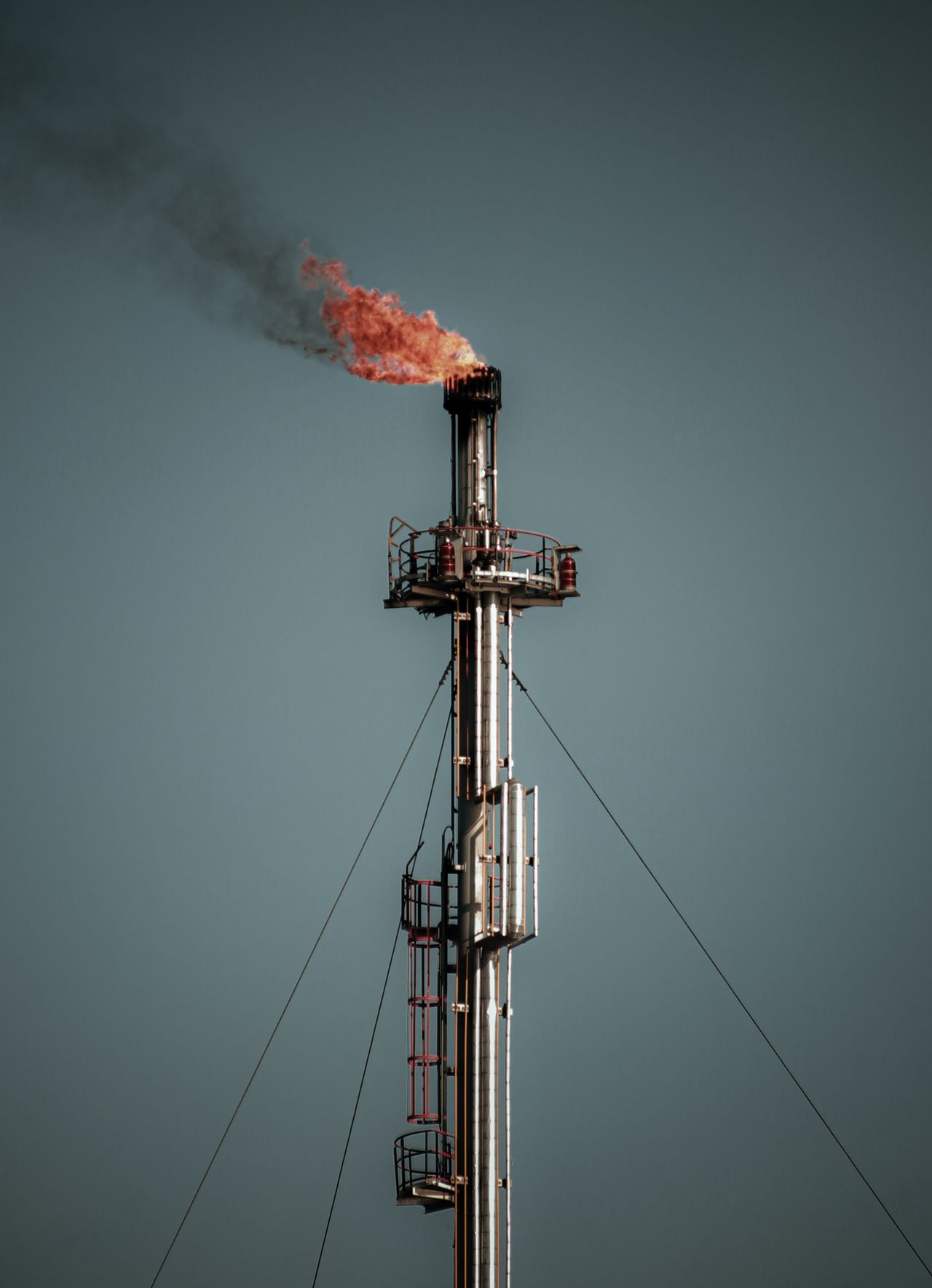 A flare stack burning against an overcast sky