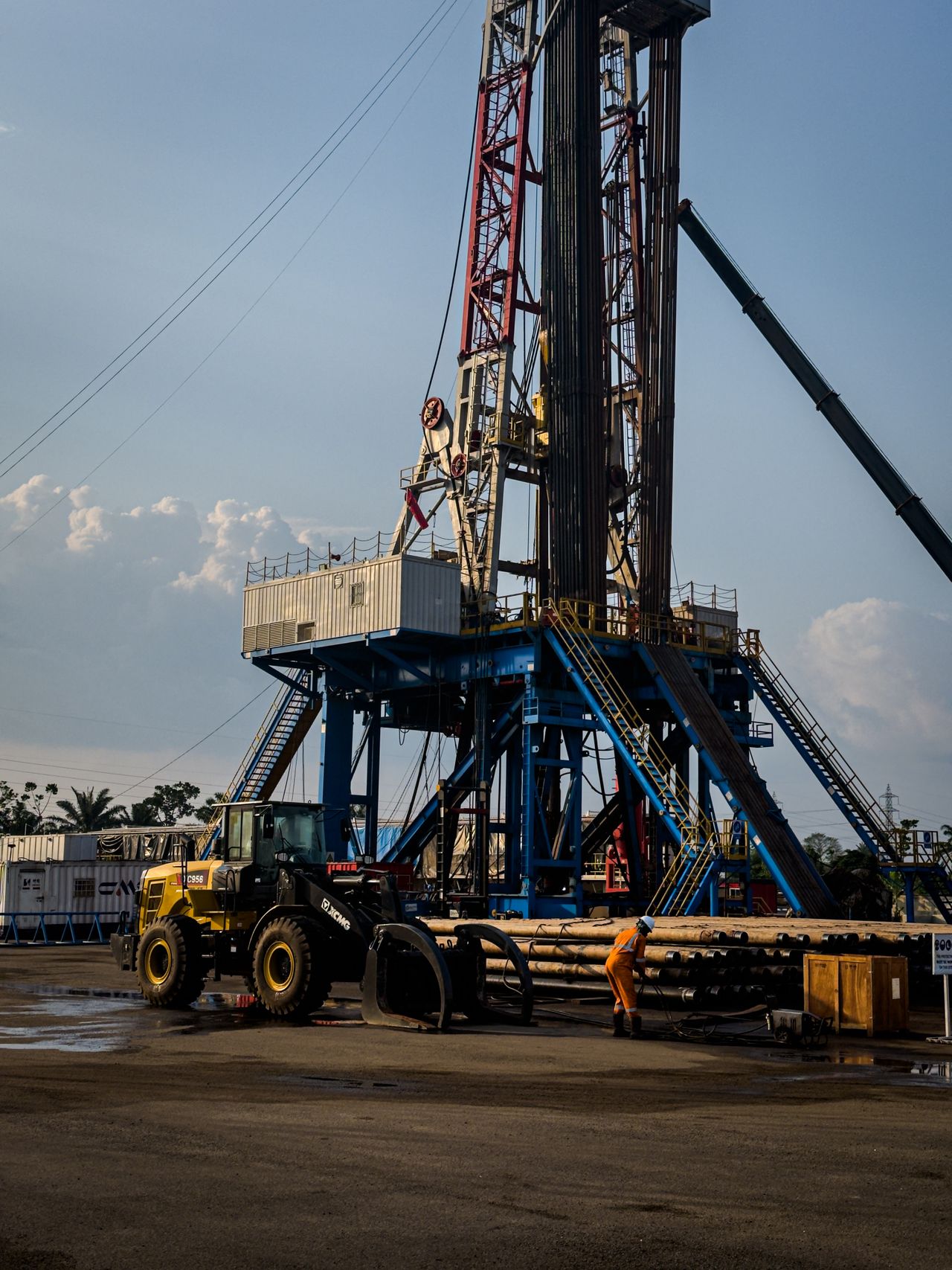 A land drilling rig lit at dusk with equipment on the lease