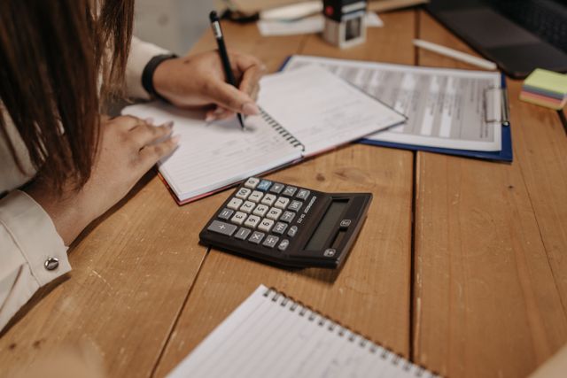 Writing up a set of figures beside a calculator, from the Marlowe & Fen Bookkeeping example site