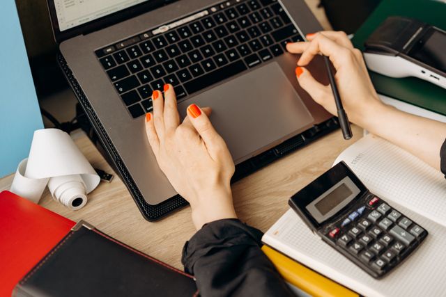 Working through a set of books on a laptop beside a calculator