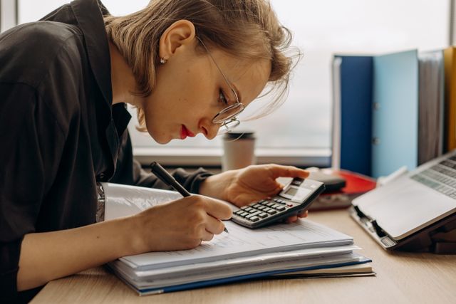 Working through a stack of ledgers and statements at a desk