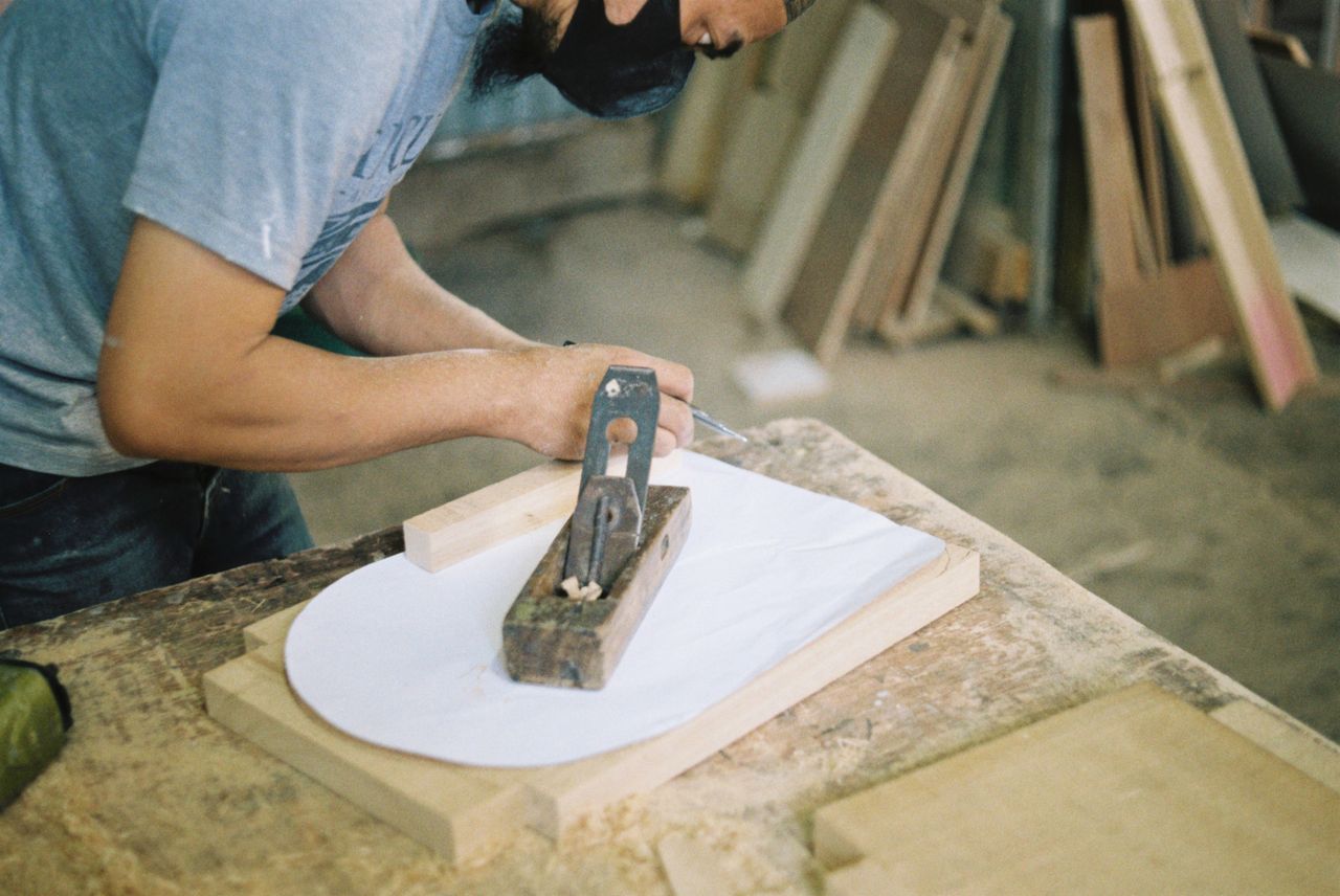 A hand plane being run along a board on the bench