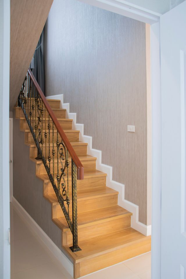 A timber staircase with a wrought-iron balustrade and wooden handrail